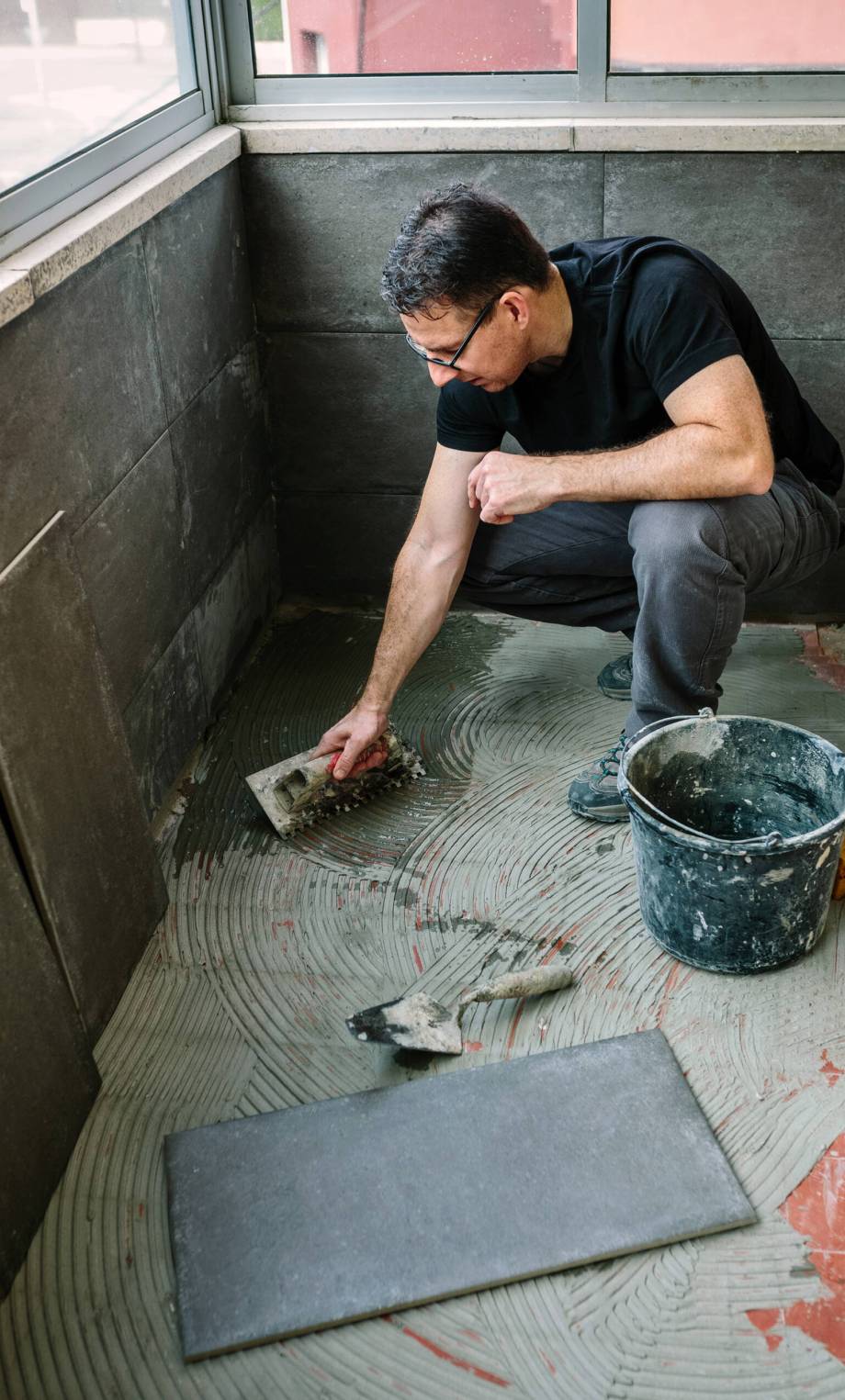 Workman laying a new tile floor on a terrace